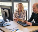 An area office member of staff sat with and supporting a customer at a computer.