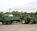 A green tractor and trailer on a farm steading