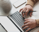 Looking over a laptop as hands type on a keyboard