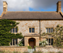 Large detached house with ivy on the walls and a stone wall in front